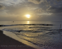 Pokojná hladina Karibského mora odráža posledné lúče slnka, rybári sa vracajú na pláž.