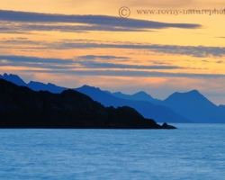 Lofoten sloping mountain ridges in the morning haze into the depths of the Atlantic and orange dawn with a fresh breeze bring wonderful feelings of presence.