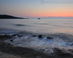 Ranné slnko preniká priehľadnými vodami mora pri pobreží Korziky a sfarbuje krajinu ružovými nádejami krásneho dňa.